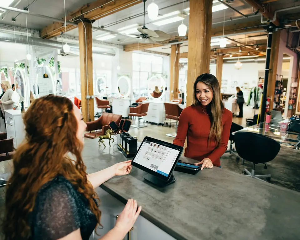 Recepción de un salón de belleza atendiendo a una clienta con la agenda en tablet